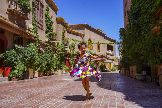 Кашгарын эртний хотын үзэмжит бүсийн Атуш гудамжид нэгэн хүүхэд хөгжим даган бүжиж байна